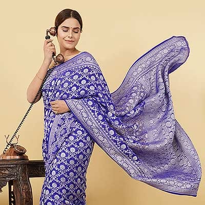 Ckstudio shot of woman wearing blue patterned saree with flowing pallu on beige background — Garment Photography