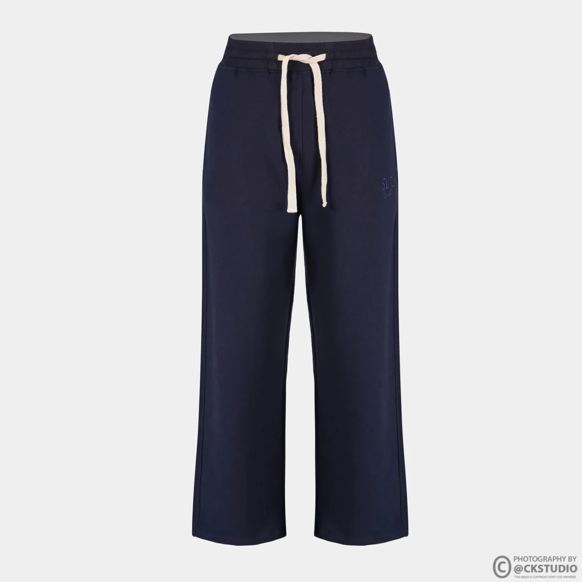 Navy drawstring trousers photographed as a ghost mannequin image on a light grey background, showing waistband shape and straight leg fall
