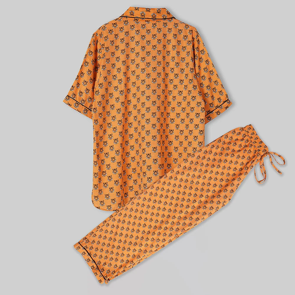 Orange printed night suit shirt and pyjama laid flat on a light grey surface, a clean flat lay frame that shows print scale and true colour