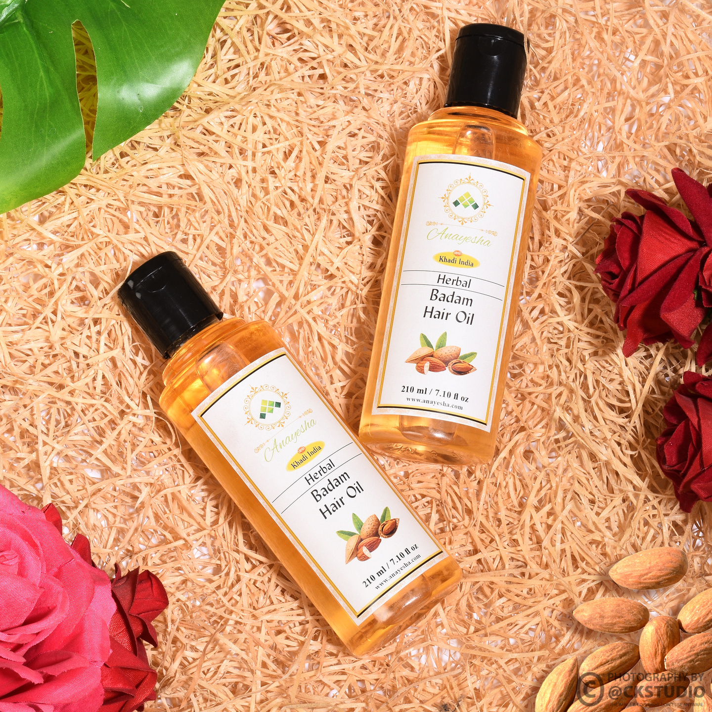 Herbal Badam hair oil bottles styled with almonds and flowers