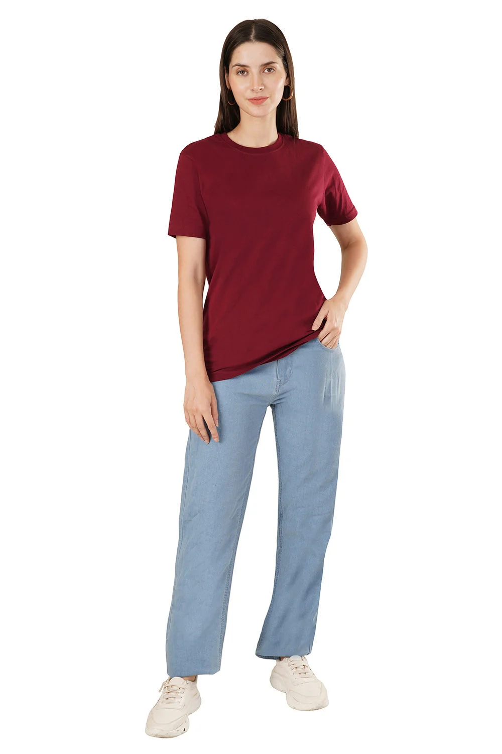 Female model in a burgundy round-neck t-shirt and light blue jeans shot full length on a white background for a fashion catalogue front angle