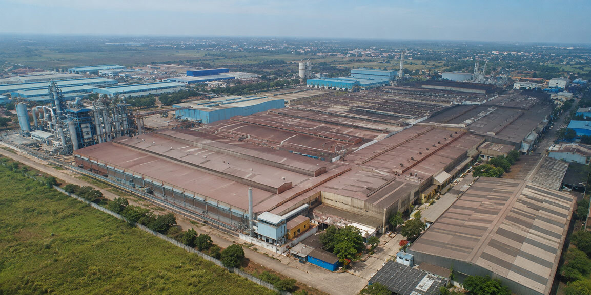 Wide aerial drone view of a large industrial manufacturing plant and factory rooftops captured for corporate film production in India