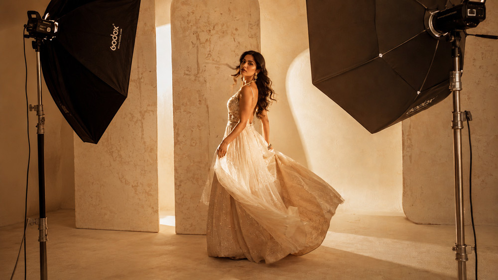 Editorial fashion photography of an Indian female model in a flowing designer gown, cinematic golden rim light, ivory magazine backdrop, luxury Delhi studio shoot by Ckstudio, Vogue-style high fashion aesthetic 2026