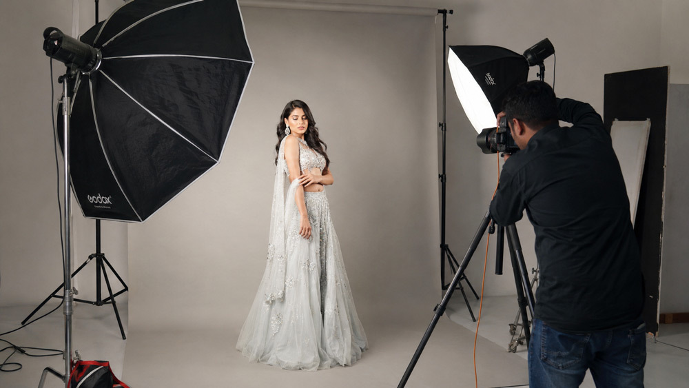 Professional fashion photography studio setup in Delhi NCR with large octabox softbox lighting, medium format camera on tripod, model wearing designer garment on infinity cyclorama backdrop, high-end editorial shoot behind the scenes