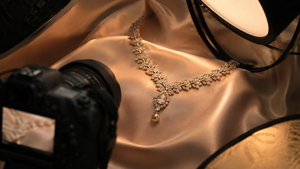 Ultra-premium editorial macro photograph of a luxurious diamond and gold necklace laid on a champagne silk backdrop with cinematic side lighting for the Ckstudio jewellery photography guide 2026