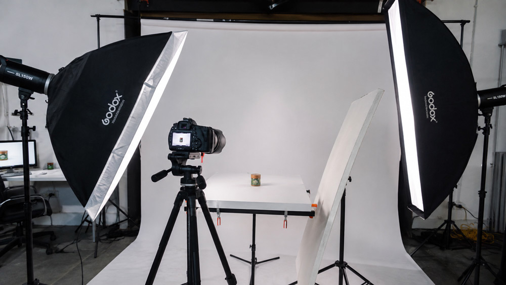 Studio softbox lighting setup with continuous LED panels and a bounce card positioned around a product on white cyclorama for professional ecommerce catalogue photography