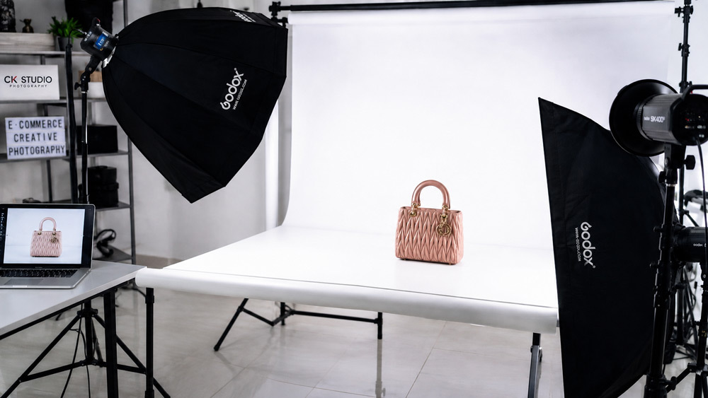 Photographer capturing high-resolution product photography on pure white cyclorama with Godox strobe lighting for Amazon and Flipkart marketplace compliance at Delhi NCR studio