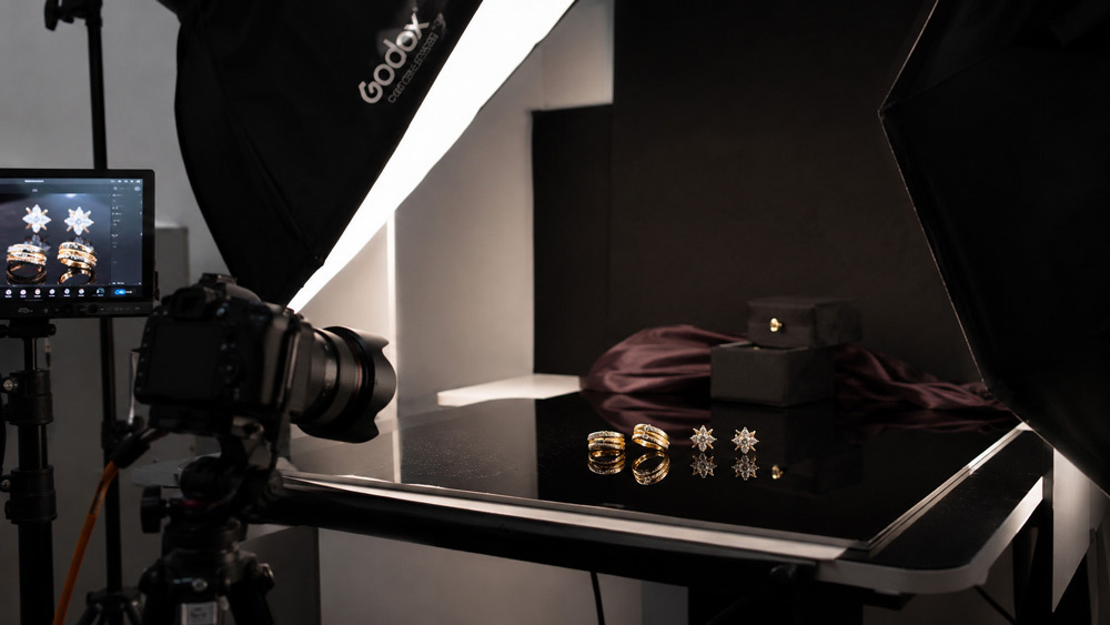 Professional studio jewellery photography setup showing gold rings and diamond earrings on dark reflective surface with softbox lighting by Ckstudio Delhi NCR