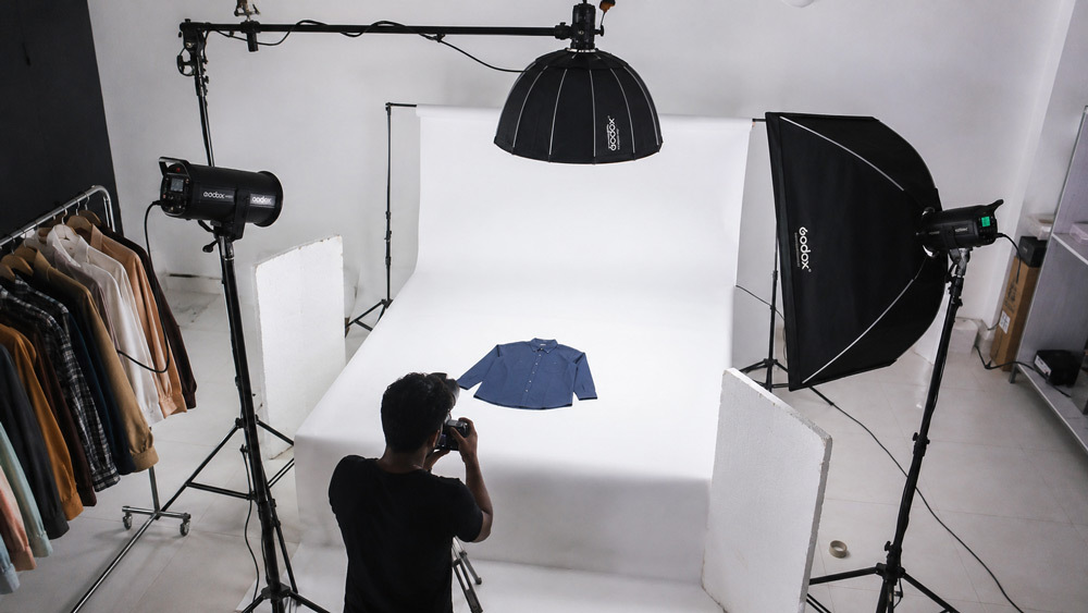 Overhead studio scene of professional ecommerce photography setup with white cyclorama, strobe lighting, and premium fashion product being shot for Amazon and Myntra catalog by Ckstudio Delhi NCR