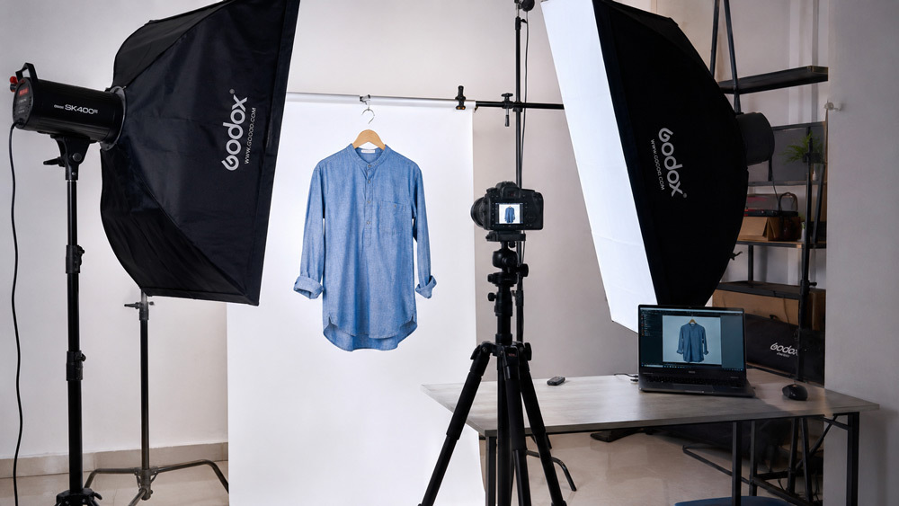 Professional ecommerce photography studio scene showing softbox lighting, camera on tripod, and a fashion garment being photographed on a white background for Myntra and Ajio catalog by Ckstudio Delhi NCR