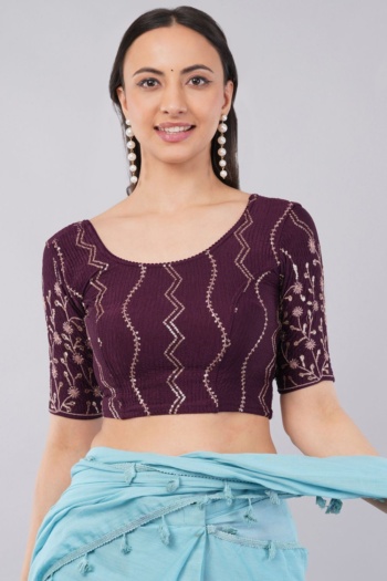 Model wearing a purple embroidered top with a light blue drape on a plain background — Ckstudio; Commercial Product Photography.