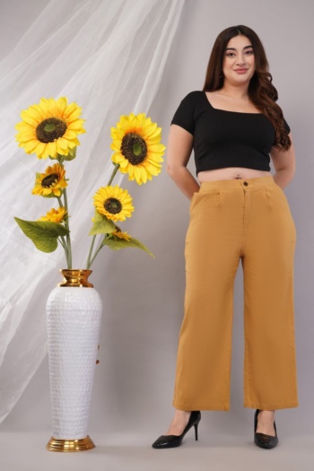 Ckstudio shot of model wearing black crop top and mustard pants on gray background with sunflowers — Commercial Product Photography