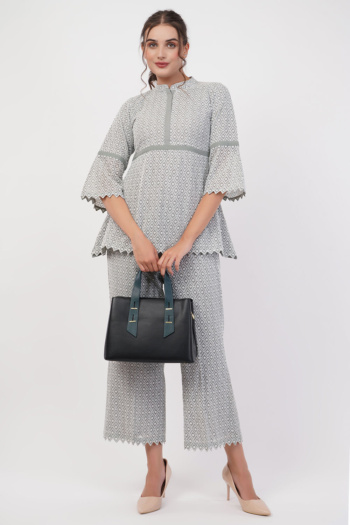 B) model wearing patterned two-piece outfit holding black handbag, shot on white background — Ckstudio; Commercial Product Photography