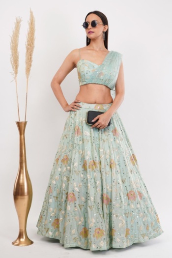 B) model wearing floral lehenga, standing beside tall golden vase, shot — Ckstudio, Commercial Product Photography