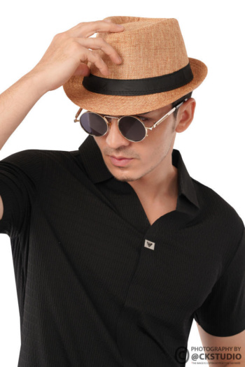 A stylish model wearing a black shirt and hat against a plain background — Ckstudio; Commercial Product Photography.