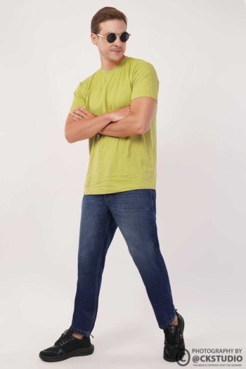 Ckstudio shot of man wearing green t-shirt and blue jeans on plain light background — Fashion Photography