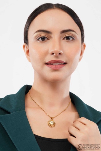 Ckstudio shot of gold pendant necklace on model wearing dark green blazer on white background, Jewellery Photography