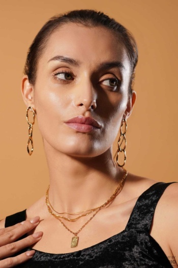 Shot of model wearing gold earrings and layered necklace on warm beige background — Ckstudio Jewellery Photography