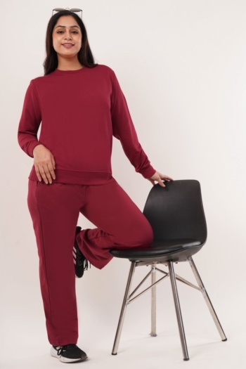 Burgundy tracksuit worn by model, black chair on white background, Commercial Product Photography shot — Ckstudio